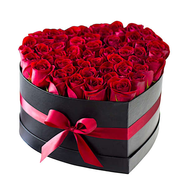Heart-shaped box filled with red roses and tied with a pink ribbon
