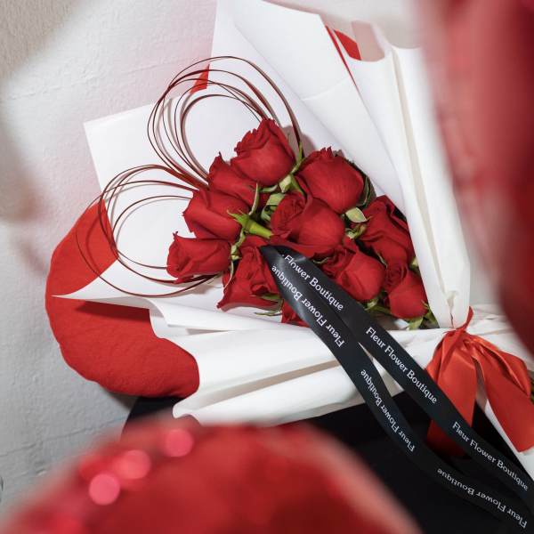 Bouquet of red roses wrapped in white paper with a red ribbon