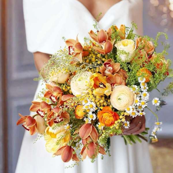 Bride holding a bouquet of orange and cream flowers