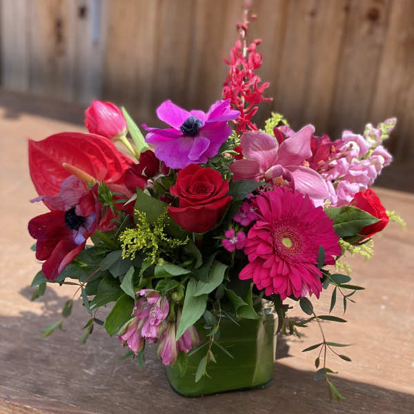 Bright pink and red mixed bouquet in a green glass vase