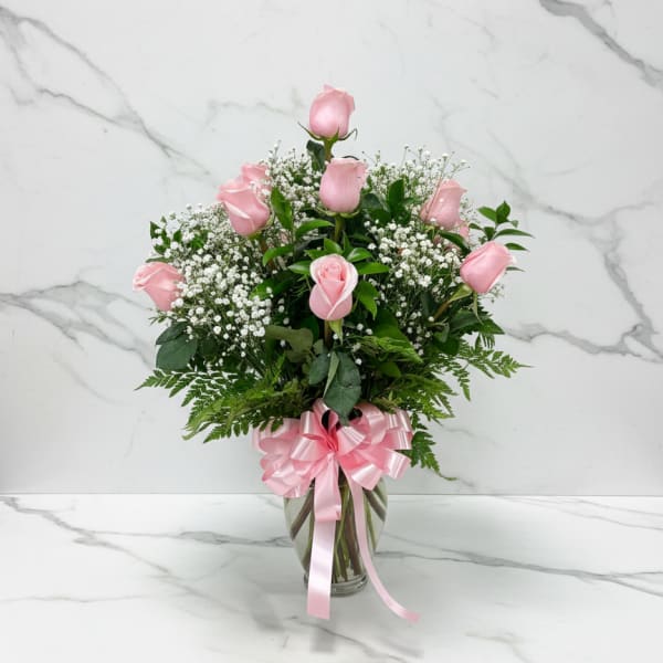 Pink roses in a glass vase with a pink ribbon bow