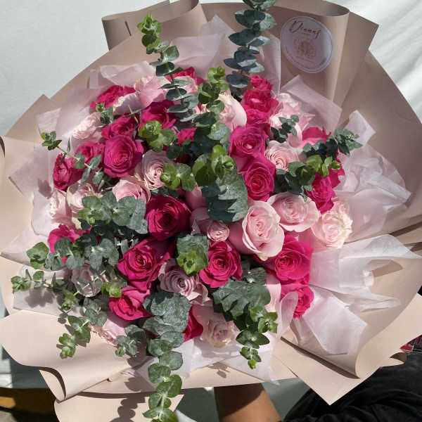 Bouquet of pink and hot pink roses with eucalyptus in blush wrapping
