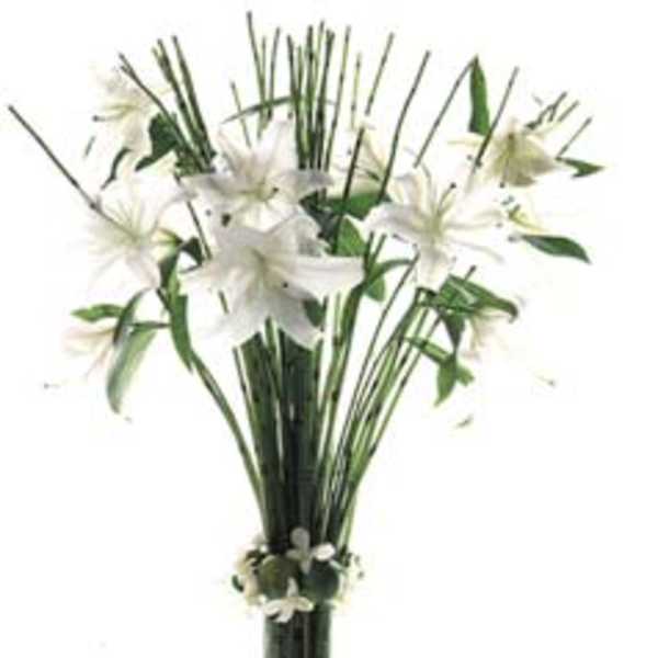 White lilies in a tall glass vase with greenery