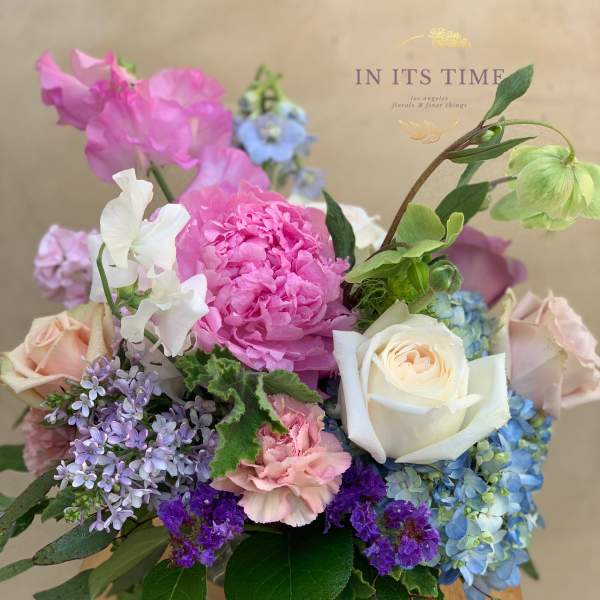 Mixed bouquet of pink, white, blue, and purple flowers in a glass vase