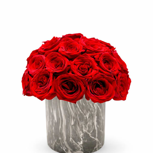 Compact arrangement of red roses in a gray marble-patterned cylinder vase