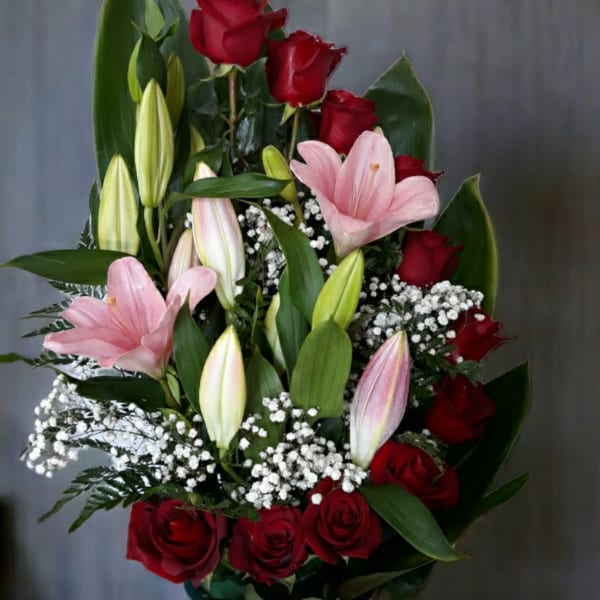 Red roses and pink lilies in a vase with baby's breath