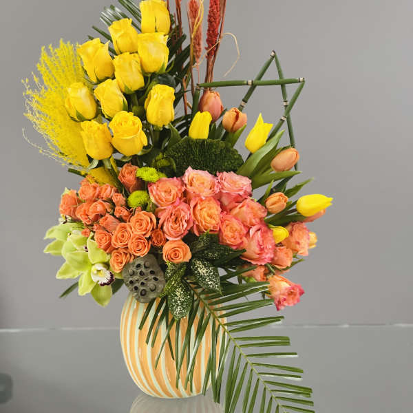 Mixed bouquet of yellow and peach flowers in a striped vase