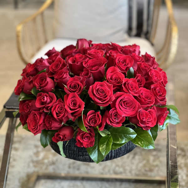 Round bouquet of red roses in a black basket