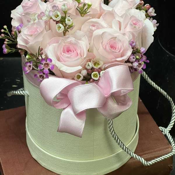 Pink roses in a round hatbox with a satin bow