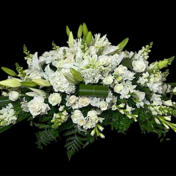 White floral casket spray with lilies and roses