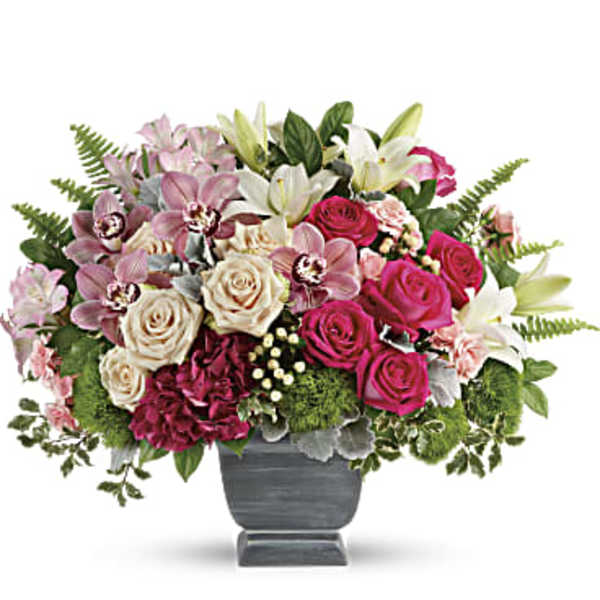 Mixed bouquet of pink roses, lilies, and orchids in a gray vase