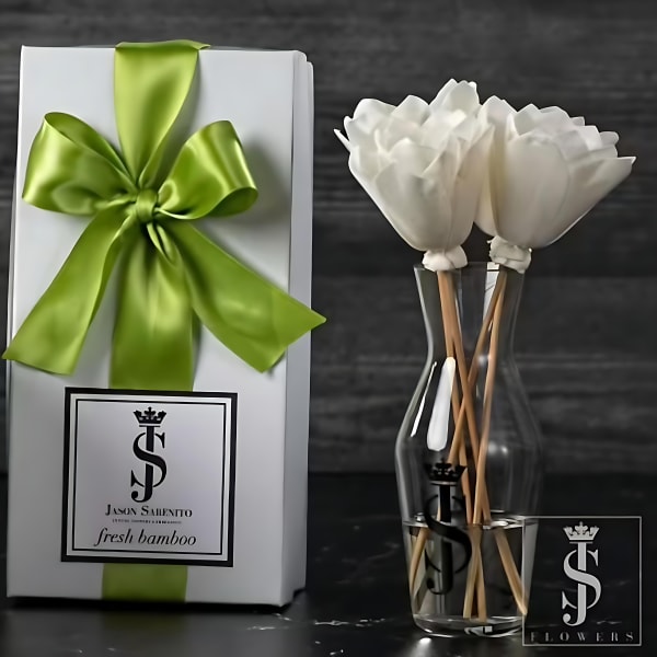 White flowers in a clear vase beside a gift box with a green ribbon