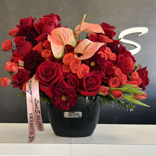 Red rose and anthurium arrangement in a black vase