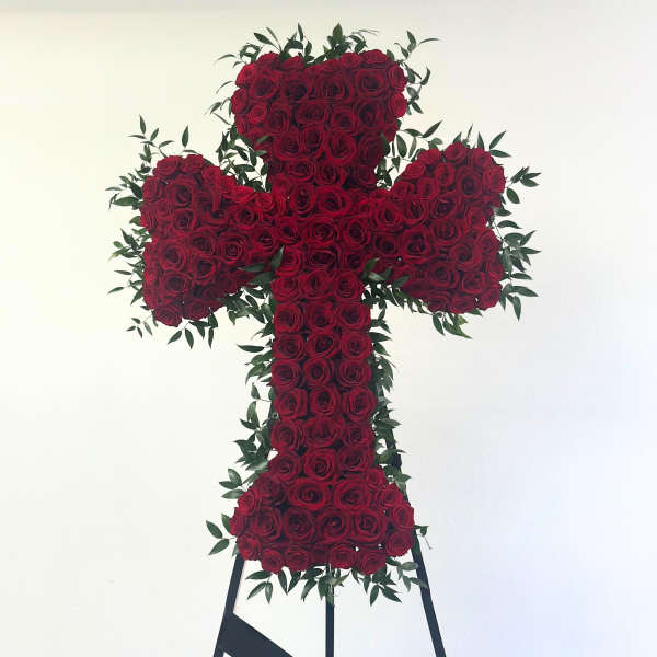 Cross-shaped arrangement of red roses with greenery on a stand