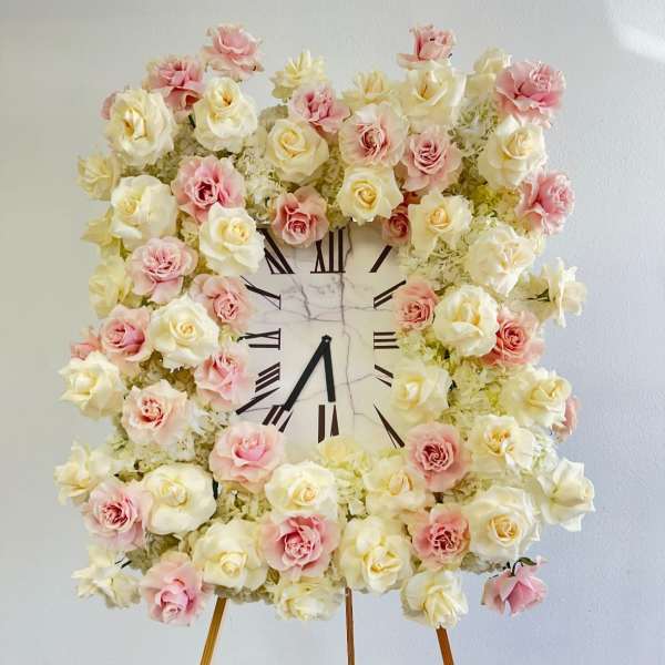 Floral clock display with pink and cream roses on an easel