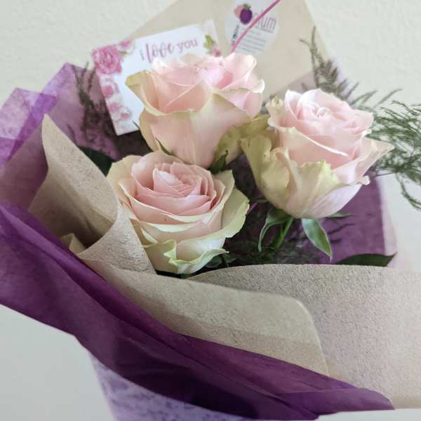 Bouquet of pale pink roses wrapped in purple and beige paper