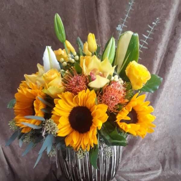 Sunflower and lily bouquet in a striped glass vase