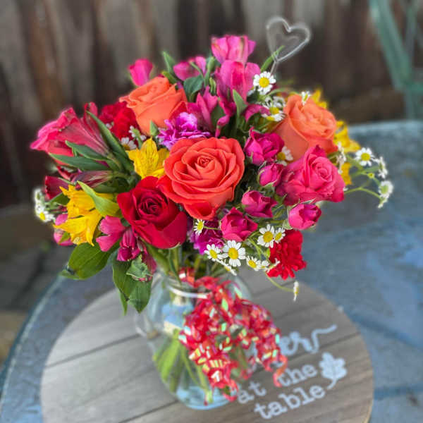 Mixed bouquet of roses and bright flowers in a glass vase