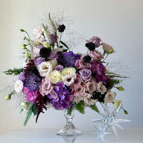 Lavender and pink floral arrangement in a clear glass pedestal vase