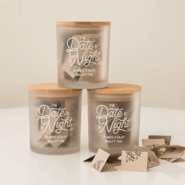 Three frosted jars with wooden lids labeled Date Night Jar