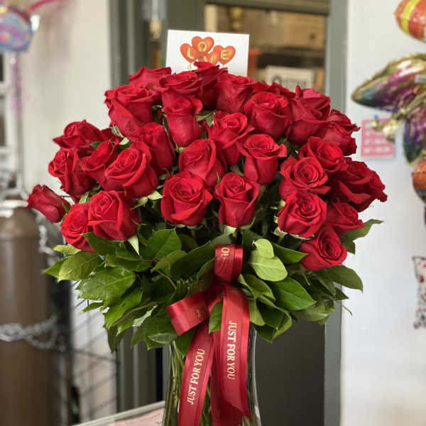 Bouquet of red roses in a glass vase with a red ribbon