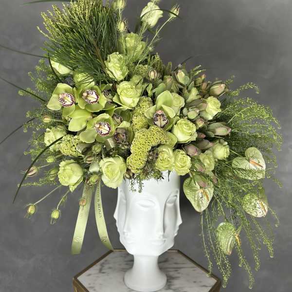 Lime-green floral arrangement in a white sculptural vase
