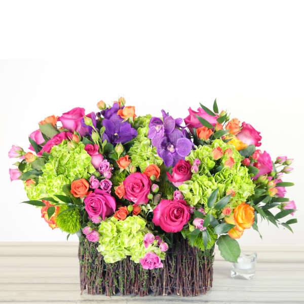 Colorful bouquet of roses, hydrangeas, and orchids in a twig basket