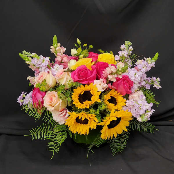 Mixed bouquet with roses, sunflowers, and lavender blooms in a vase