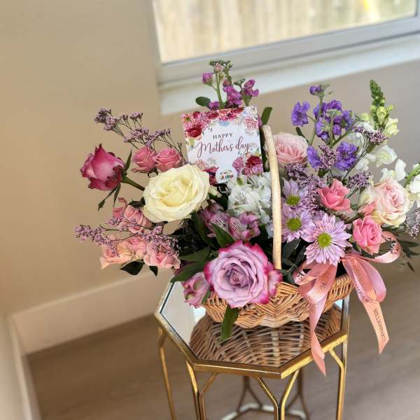 Basket arrangement of roses, daisies, and snapdragons with a Mother's Day card
