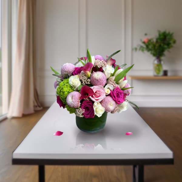 Pink and white mixed flower arrangement in a green vase