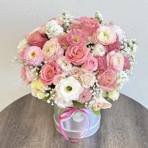 Pink and white mixed flower bouquet in a round box with ribbon