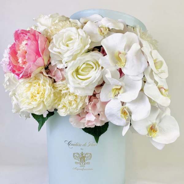 Pink and white flowers arranged in a pale blue hat box