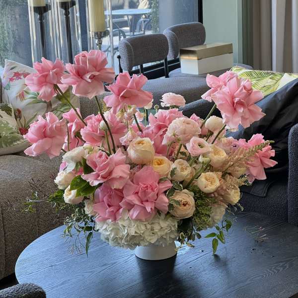 Pink and cream floral arrangement in a white vase on a table