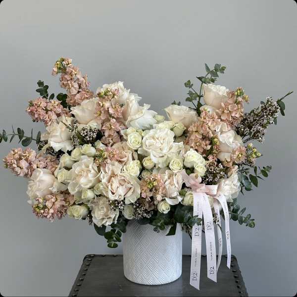 Large bouquet of cream and blush roses in a white textured vase