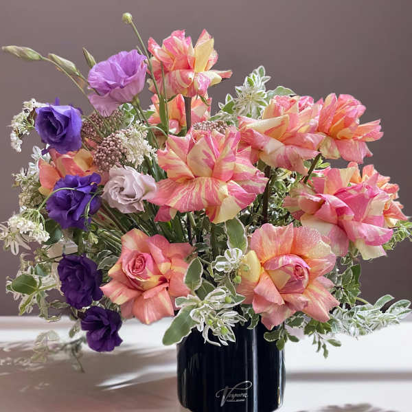 Bouquet of pink, peach, and purple flowers in a black vase