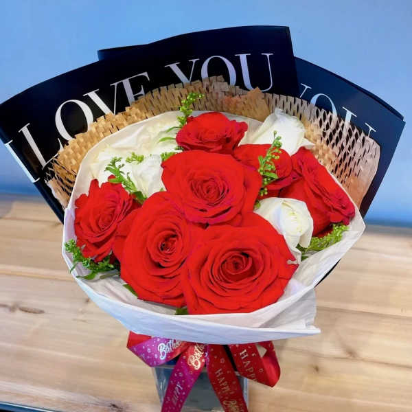 Bouquet of red and white roses wrapped in paper with a ribbon