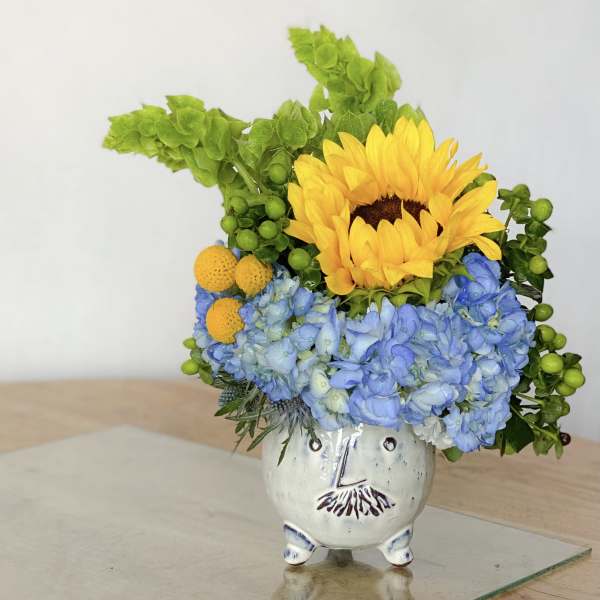 Sunflower and blue hydrangea arrangement in a small ceramic vase