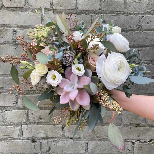 Handheld bouquet of white and blush flowers with succulents