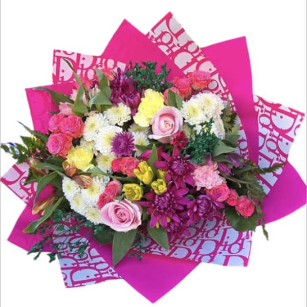 Bright mixed bouquet with pink, white, and yellow flowers wrapped in hot pink paper