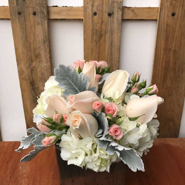 Pastel roses and hydrangeas arranged in a wooden box