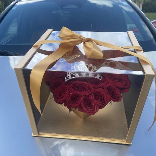 Heart-shaped box of red roses with a gold ribbon and tiara