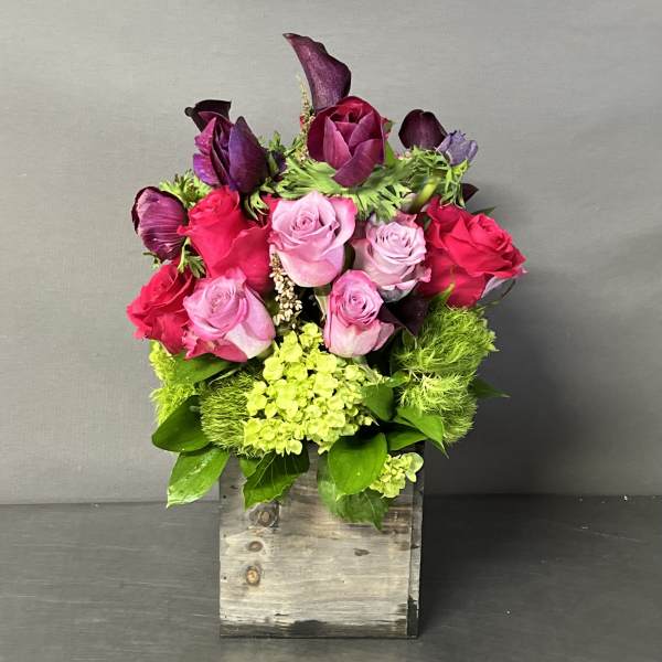 Bouquet of pink and red roses with purple calla lilies in a wooden box