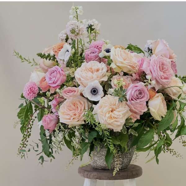 Large pastel bouquet of roses and white anemones in a textured vase