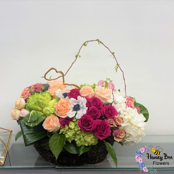 Mixed bouquet of roses, hydrangeas, and white blooms in a low basket