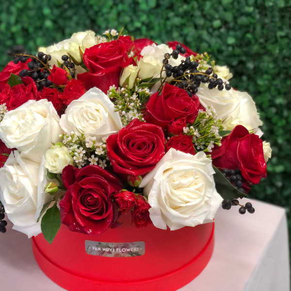 Red and white rose arrangement in a red hat box