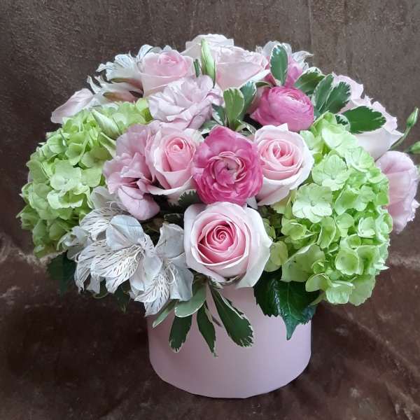 Pink roses and green hydrangeas arranged in a pale pink box