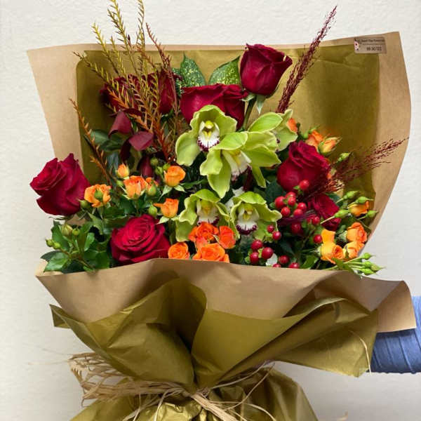 Bouquet of red roses and green orchids wrapped in gold paper