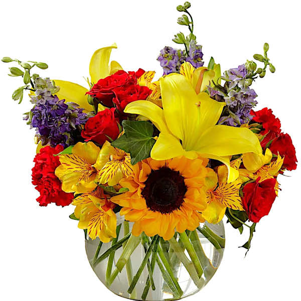 Bright mixed bouquet with lilies, sunflowers, roses, and purple flowers in a glass vase