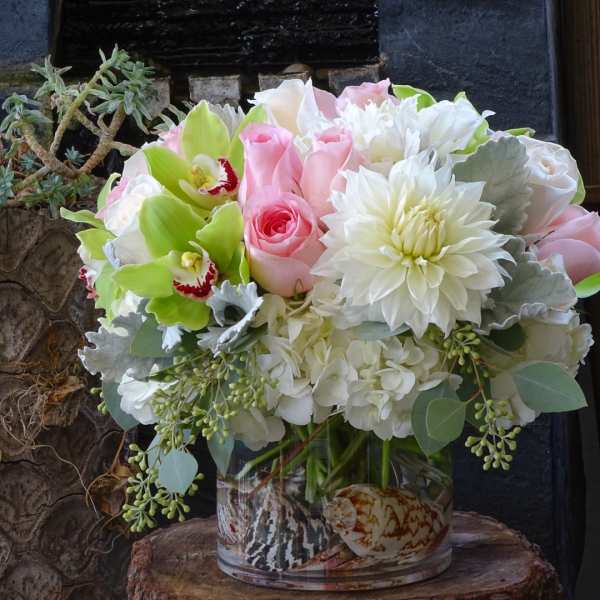 Pink roses and white flowers arranged in a glass vase