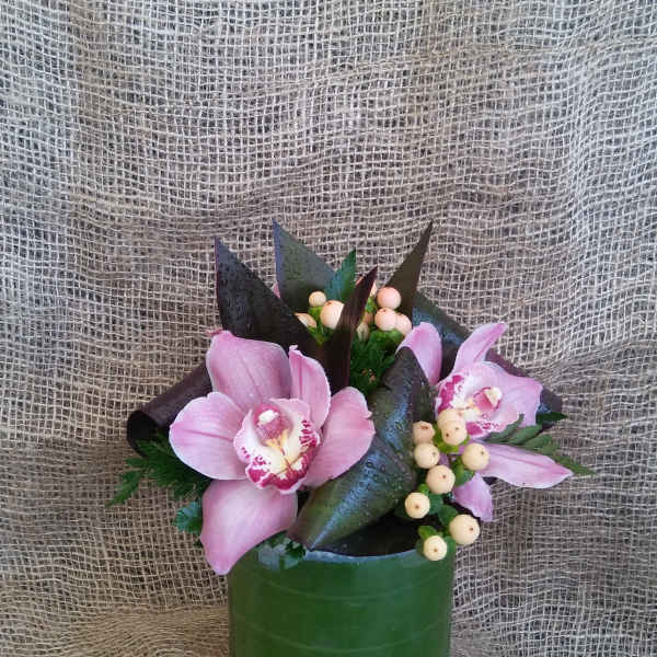 Pink orchids arranged in a green cylindrical vase